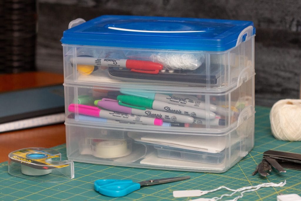 A snapware box sits stacked three high, full of everything a vendor needs for a successful show, including pens, price tags, etc.