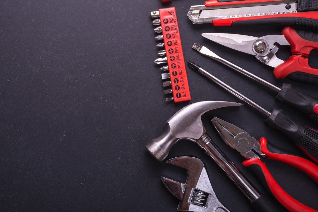 A dark background with a bunch of red handled tools laying on the right side.