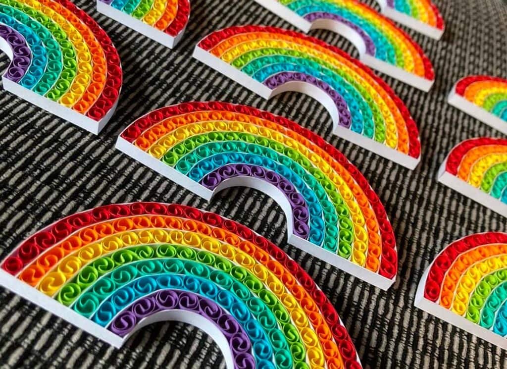 Rows of quilled rainbows against a dark background, all by Obsidian Rose Design