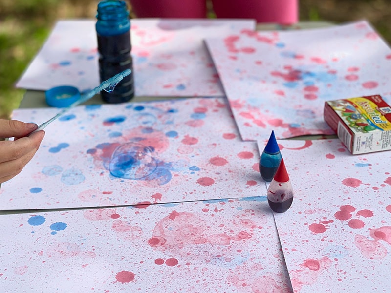 A bunch of papers covered in red and blue blow bubble art. A fresh bubble sits on the paper.