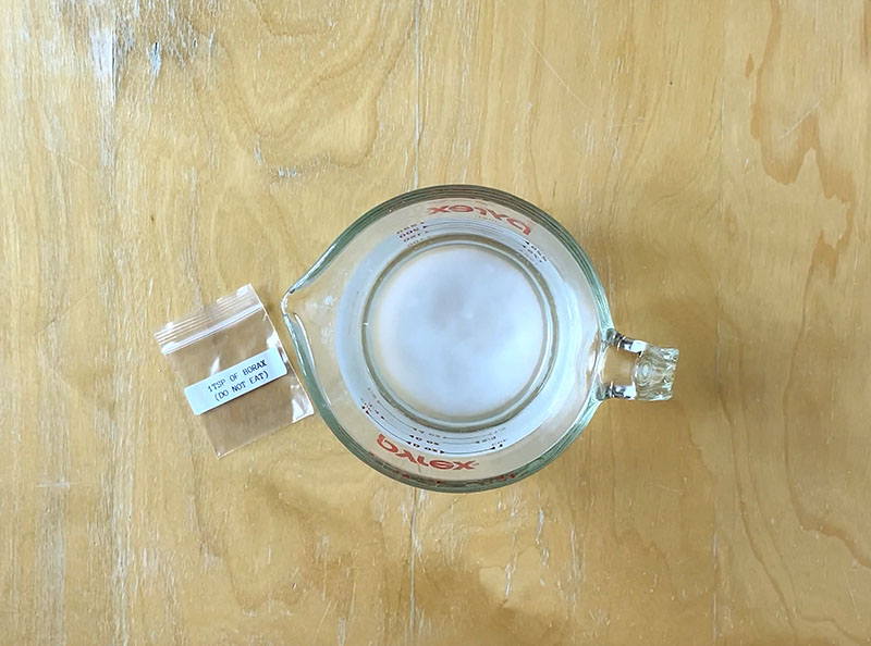 empty borax packets with the text "1 tsp borax do not eat" sit next to a container of borax mixture