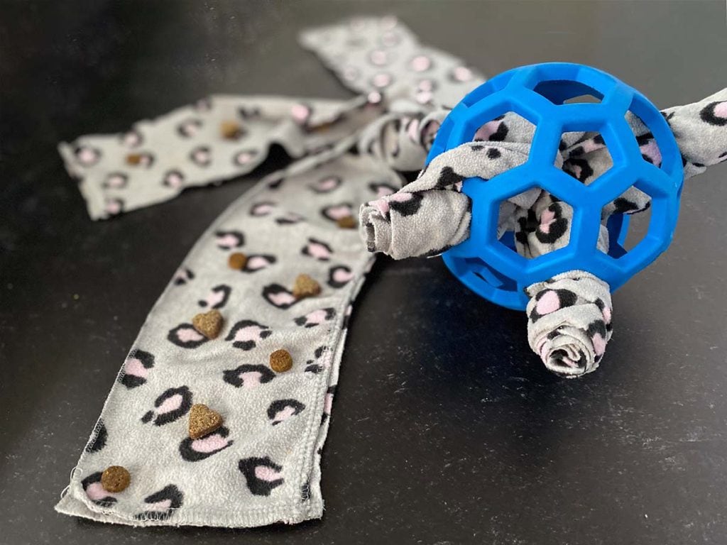 A blue holee roller ball is stuffed with fleece. The pieces are extended out and contain bits of kibble and treats