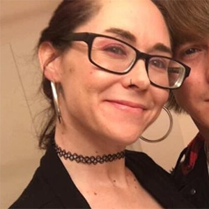 Photo of a woman with glasses smiling, Maci from Mark Your Worth