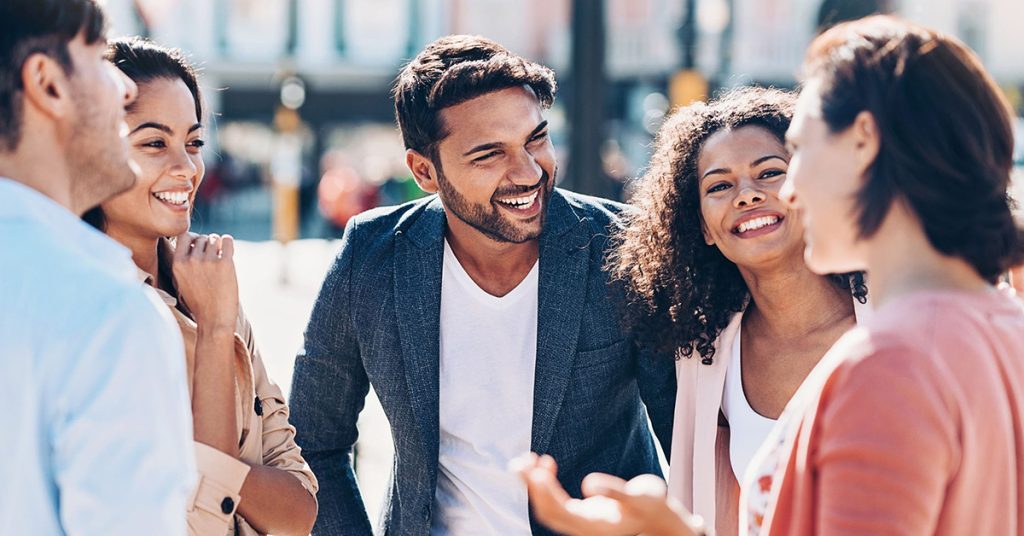 A group of people stand around outside laughing