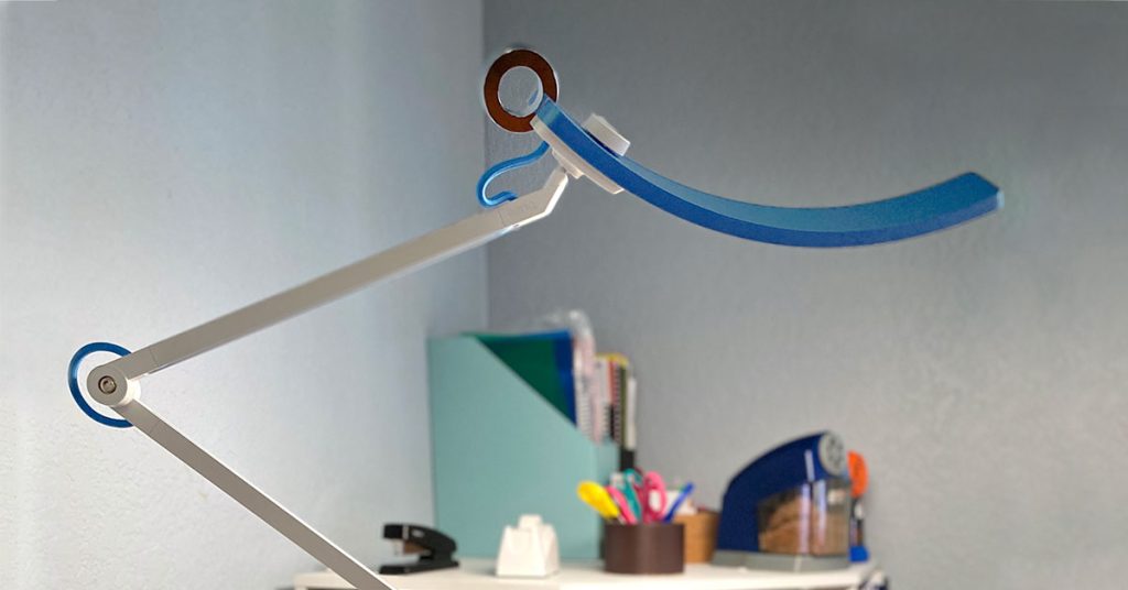 BenQ e-reading floor lamp in the light blue color is posed over a small corner bookshelf. The light is illuminating everything on the bookshelf.