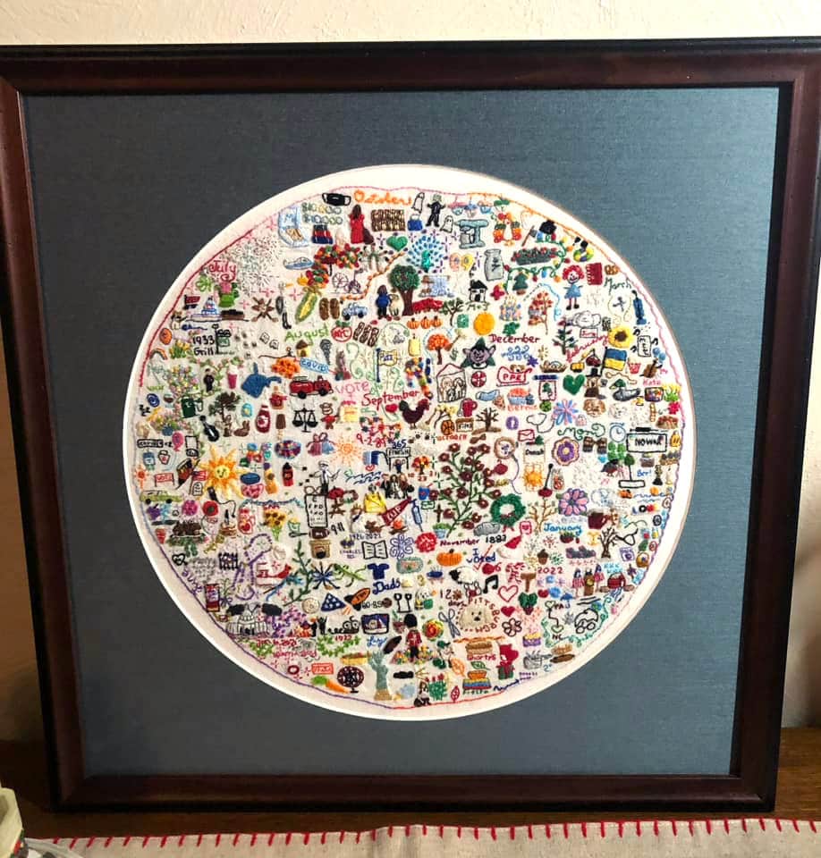 A finished embroidery journal has been put into a matted glass frame